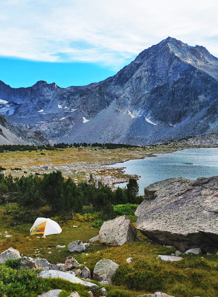 A backpacking tent sits in a meadow above Macon Lake in the Wind River Range, Wyoming.